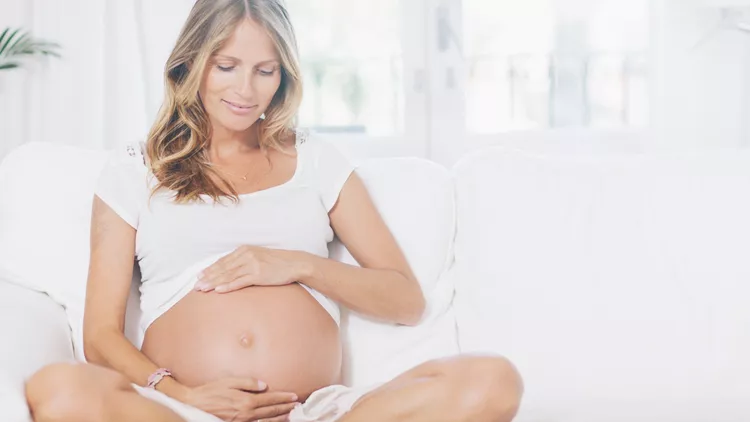 Pregnant woman relaxing on living room.